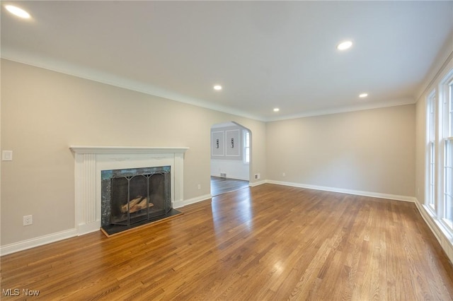 17607 Scottsdale Blvd, Shaker Heights, OH 44120 - unfurnished living room featuring arched walkways, wood finished floors, baseboards, ornamental molding, and a fireplace