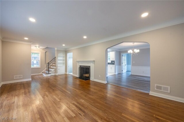 17607 Scottsdale Blvd, Shaker Heights, OH 44120 - unfurnished living room with a fireplace, wood finished floors, a chandelier, crown molding, and arched walkways