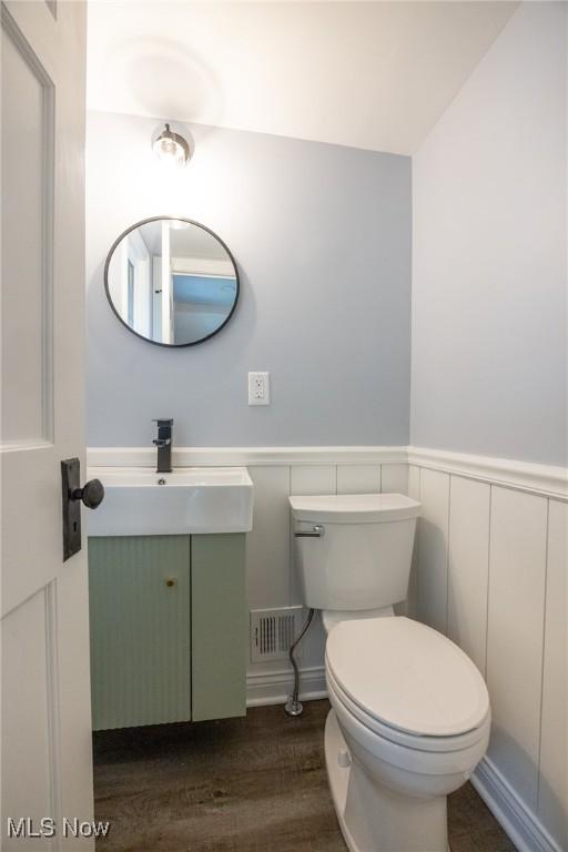 17607 Scottsdale Blvd, Shaker Heights, OH 44120 - half bathroom with vanity, toilet, a wainscoted wall, wood finished floors, and a decorative wall