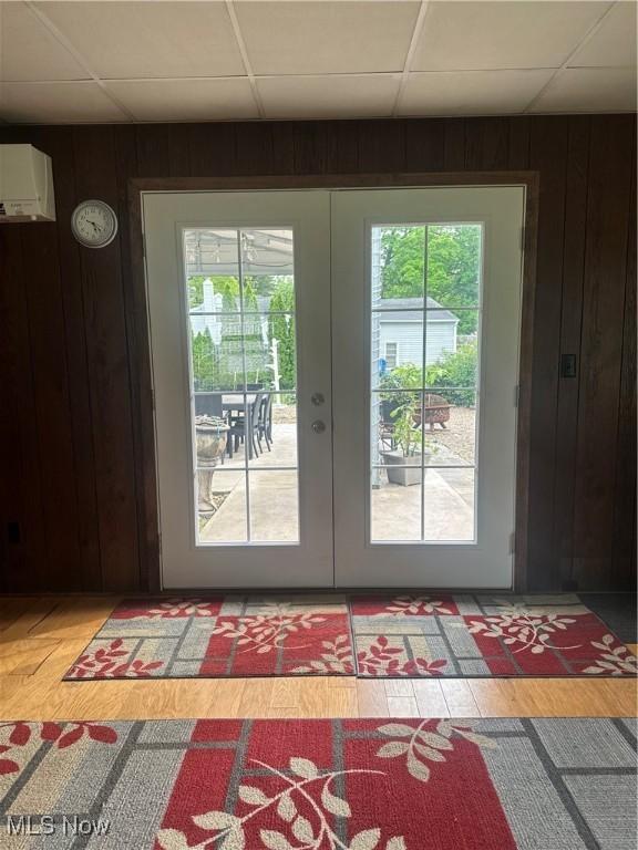 379 Wilson Mills Rd, Chardon, OH 44024 - doorway to outside with french doors, light wood-style flooring, a paneled ceiling, wooden walls, and an AC wall unit