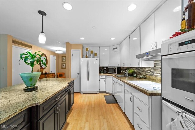 18975 Van Aken Blvd Unit 401, Shaker Heights, OH 44122 - kitchen with white appliances, under cabinet range hood, white cabinets, light wood finished floors, and decorative light fixtures