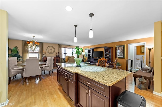 18975 Van Aken Blvd Unit 401, Shaker Heights, OH 44122 - kitchen with light wood-style flooring, decorative light fixtures, a chandelier, light stone counters, and a kitchen island
