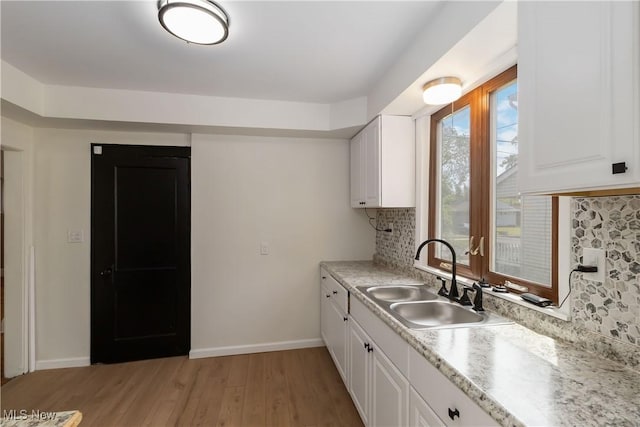 3338 E 130th St, Cleveland, OH 44120 - kitchen featuring a sink, decorative backsplash, light wood-type flooring, white cabinets, and light countertops