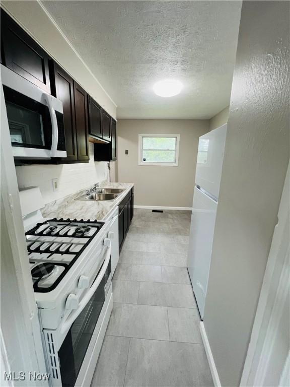4780 E 173rd St, Cleveland, OH 44128 - kitchen featuring white appliances, a sink, a textured ceiling, baseboards, and light countertops