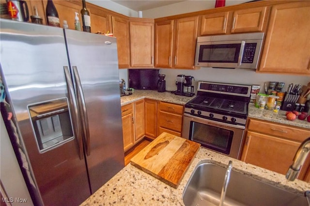 1425 Lindazzo Ave, Cleveland, OH 44114 - kitchen with appliances with stainless steel finishes, a sink, light stone countertops, and brown cabinets