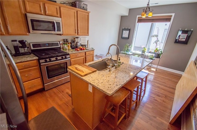 1425 Lindazzo Ave, Cleveland, OH 44114 - kitchen with stainless steel appliances, a sink, light wood-type flooring, a center island with sink, and a kitchen breakfast bar