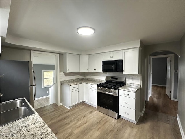 4570 N Leavitt Rd NW, Warren, OH 44485 - kitchen featuring appliances with stainless steel finishes, arched walkways, baseboards, and backsplash