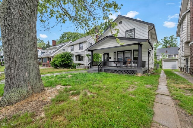 15417 Parkgrove Ave, Cleveland, OH 44110 - view of front facade with a porch, a front lawn, driveway, a residential view, and a detached garage