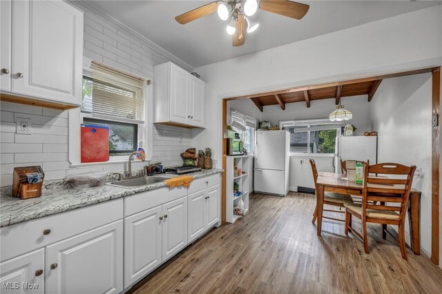15417 Parkgrove Ave, Cleveland, OH 44110 - kitchen featuring freestanding refrigerator, a ceiling fan, decorative backsplash, white cabinetry, and light wood finished floors