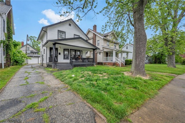 15417 Parkgrove Ave, Cleveland, OH 44110 - view of front of home with a porch, an outbuilding, a front lawn, and a detached garage