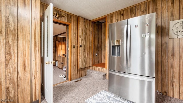73117 Deck Rd, Freeport, OH 43973 - kitchen with stainless steel fridge, wood walls, carpet floors, and brown cabinets