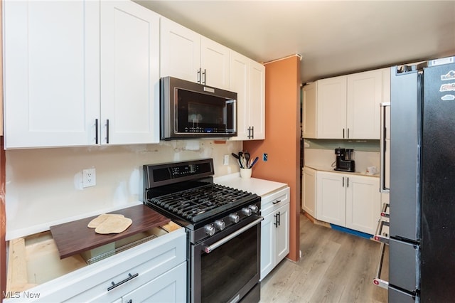 10229 State Rd, North Royalton, OH 44133 - kitchen featuring stainless steel range with gas stovetop, freestanding refrigerator, white cabinetry, and light wood-style floors