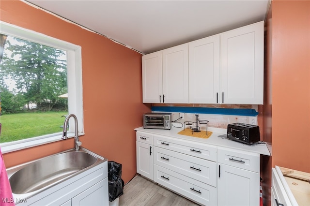 10229 State Rd, North Royalton, OH 44133 - kitchen with a sink, white cabinetry, light countertops, and light wood-style flooring