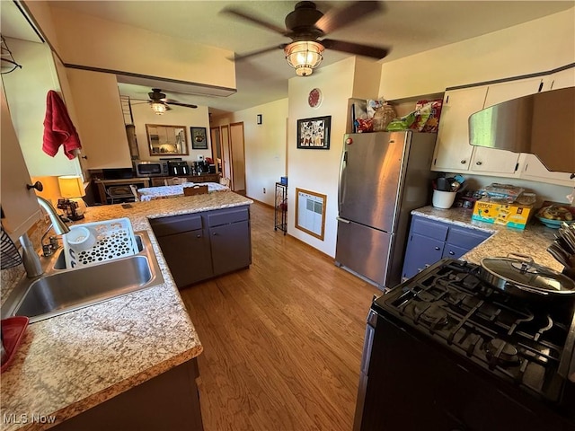 5301 S Ridge Rd W, Ashtabula, OH 44004 - kitchen with a ceiling fan, gas stove, freestanding refrigerator, a sink, and light wood-style flooring