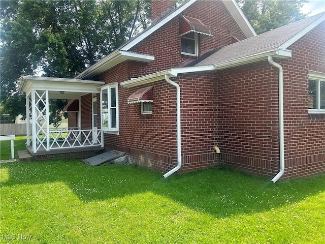 307 N 8th St, Coshocton, OH 43812 - view of property exterior featuring a porch, a lawn, and brick siding