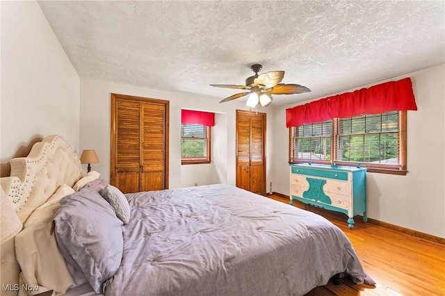 2322 Westview Rd, Cortland, OH 44410 - bedroom with multiple windows, wood finished floors, two closets, baseboards, and a textured ceiling