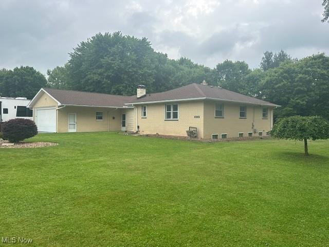 3232 Circle Dr, Cortland, OH 44410 - rear view of property with a chimney, a lawn, and a garage
