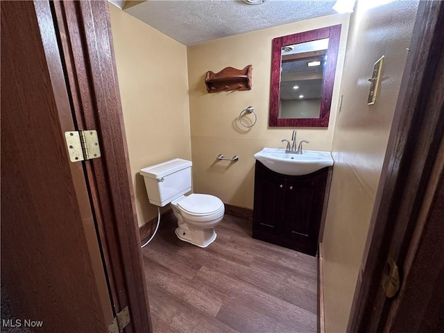 1029 Fowler Dr, Caldwell, OH 43724 - bathroom with wood finished floors, toilet, vanity, and a textured ceiling