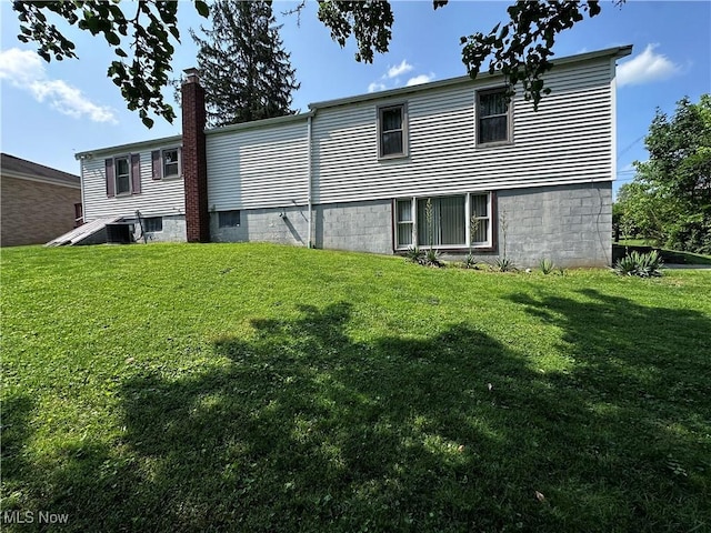 1029 Fowler Dr, Caldwell, OH 43724 - back of property featuring a lawn, a chimney, and central AC unit