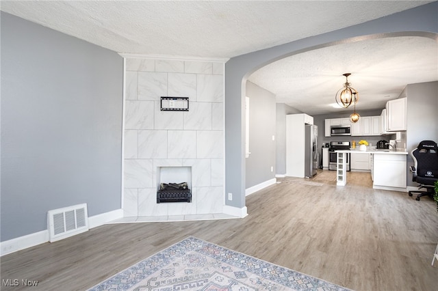 1168 Onondago Ave, Akron, OH 44305 - living room with arched walkways, a textured ceiling, light wood-type flooring, and a chandelier
