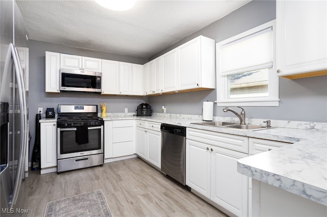 1168 Onondago Ave, Akron, OH 44305 - kitchen featuring stainless steel appliances, light wood-style flooring, white cabinetry, a textured ceiling, and light stone countertops