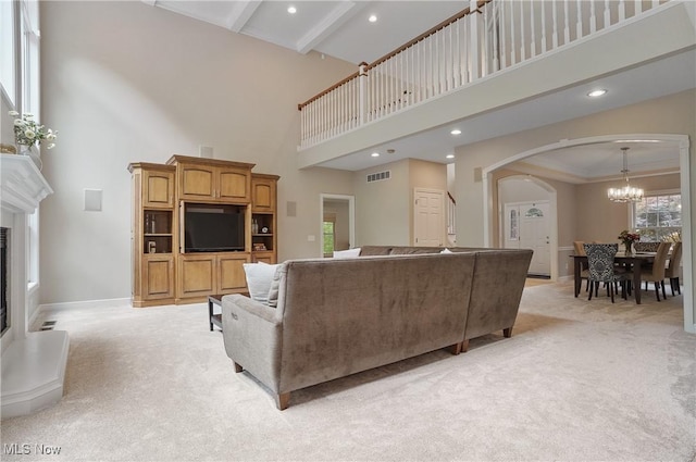 2634 Deer Ridge Run, Cuyahoga Falls, OH 44223 - living area featuring a high ceiling, arched walkways, light carpet, a chandelier, and a glass covered fireplace