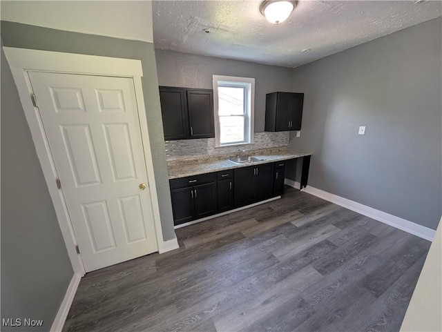 908 W 8th St, Lorain, OH 44052 - kitchen featuring a textured ceiling, light countertops, dark cabinetry, dark wood-type flooring, and decorative backsplash