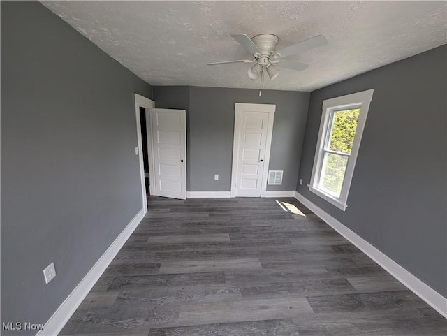 908 W 8th St, Lorain, OH 44052 - unfurnished bedroom with a textured ceiling, dark wood-style floors, and a ceiling fan