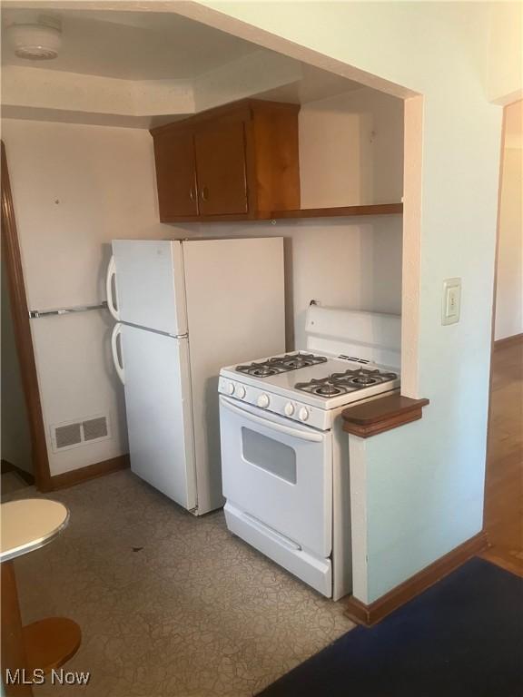 7718 Bertha Ave, Parma, OH 44129 - kitchen with white appliances, brown cabinetry, and light floors
