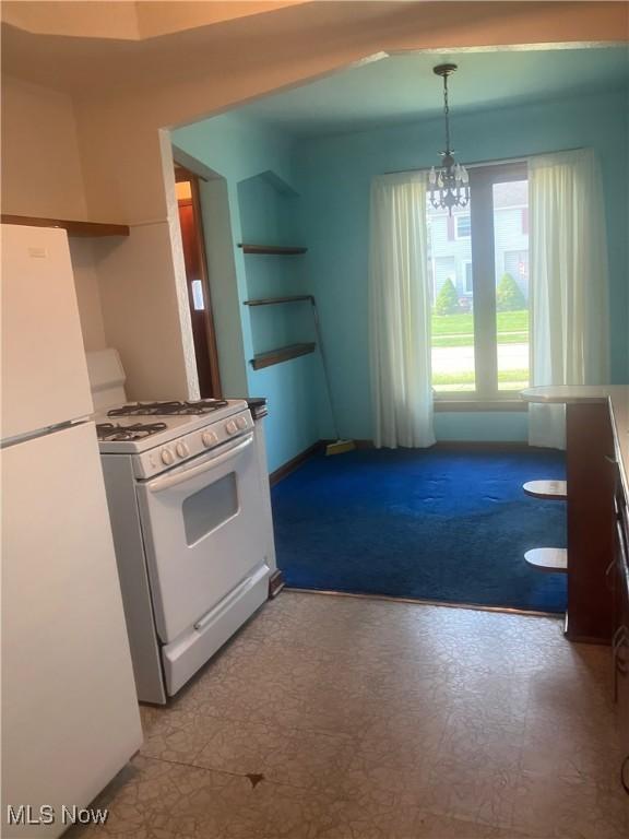 7718 Bertha Ave, Parma, OH 44129 - kitchen with white appliances, a chandelier, hanging light fixtures, tile patterned floors, and built in shelves
