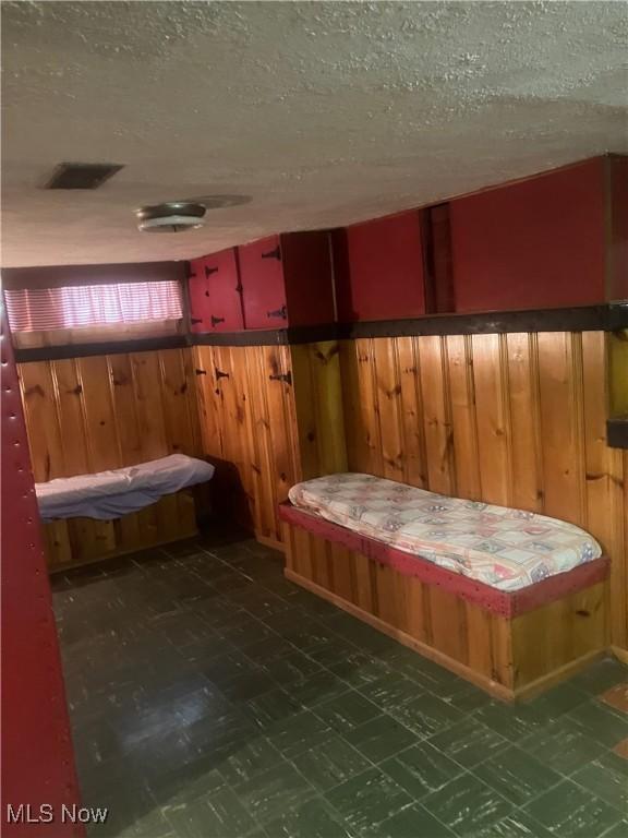 7718 Bertha Ave, Parma, OH 44129 - bedroom featuring dark flooring, a textured ceiling, and wooden walls