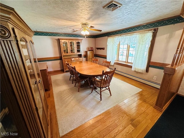 1684 Morris St, Mineral Ridge, OH 44440 - dining area with a baseboard radiator, a textured ceiling, wood-type flooring, a ceiling fan, and ornamental molding