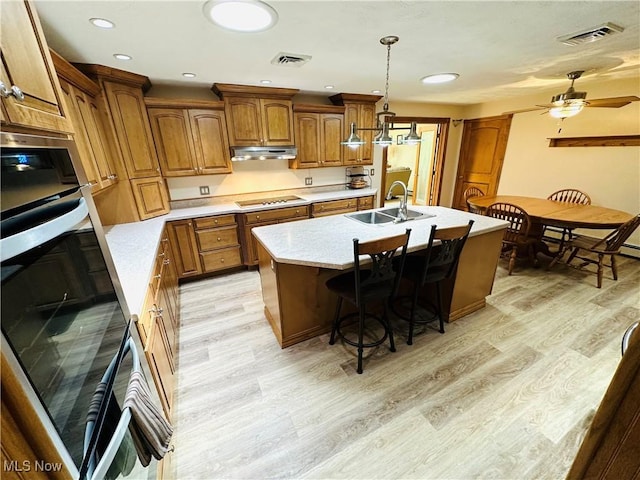 1684 Morris St, Mineral Ridge, OH 44440 - kitchen featuring brown cabinetry, light wood-style floors, ceiling fan, an island with sink, and recessed lighting