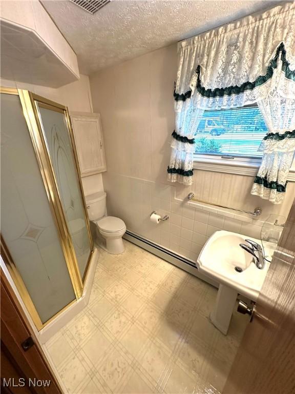 1684 Morris St, Mineral Ridge, OH 44440 - full bathroom featuring a shower stall, a textured ceiling, baseboard heating, and tile patterned floors