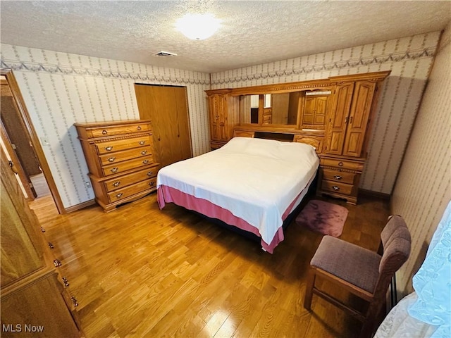 1684 Morris St, Mineral Ridge, OH 44440 - bedroom with wallpapered walls, wood finished floors, a textured ceiling, and a closet