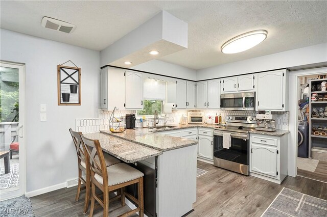 53 Joel Dr, Mogadore, OH 44260 - kitchen with stainless steel appliances, a peninsula, white cabinets, tasteful backsplash, and recessed lighting