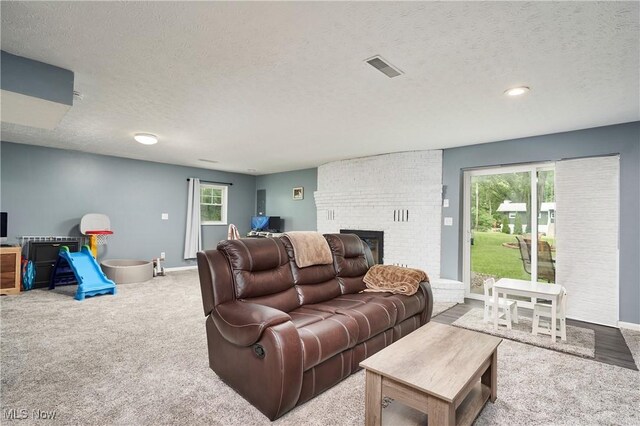 53 Joel Dr, Mogadore, OH 44260 - carpeted living room with a textured ceiling, a brick fireplace, and healthy amount of natural light