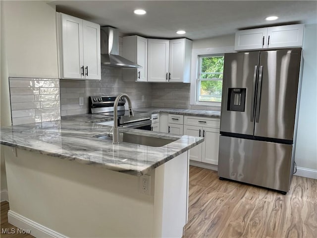 124 W 29th St, Lorain, OH 44055 - kitchen with appliances with stainless steel finishes, wall chimney exhaust hood, a peninsula, light wood finished floors, and recessed lighting