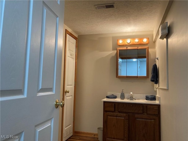 454 Lincoln Ave NW, Carrollton, OH 44615 - half bathroom with vanity, a textured ceiling, and wood finished floors