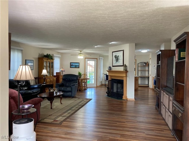 454 Lincoln Ave NW, Carrollton, OH 44615 - living area with dark wood finished floors, a textured ceiling, a ceiling fan, and a fireplace