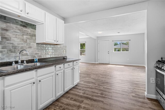 2914 Maple St, Norton, OH 44203 - kitchen with stainless steel gas stove, dark countertops, backsplash, white cabinetry, and dark wood finished floors