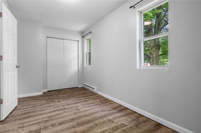 2914 Maple St, Norton, OH 44203 - unfurnished bedroom featuring a baseboard heating unit, wood finished floors, and a closet