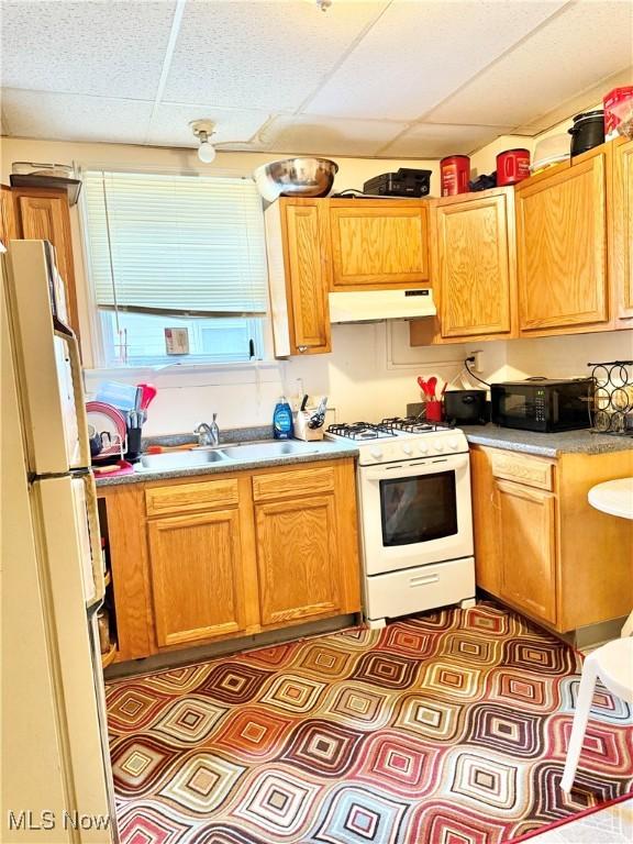 2320 22nd St SW, Akron, OH 44314 - kitchen featuring white appliances, a drop ceiling, under cabinet range hood, tile patterned floors, and light countertops