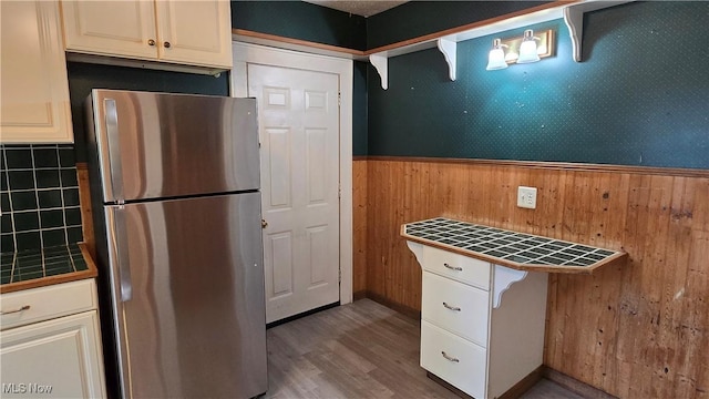 1014 20th St, Parkersburg, WV 26101 - kitchen with freestanding refrigerator, tile counters, wooden walls, a wainscoted wall, and wood finished floors