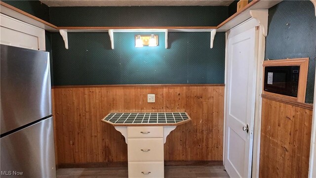 1014 20th St, Parkersburg, WV 26101 - kitchen with freestanding refrigerator, tile counters, wooden walls, wood finished floors, and black microwave