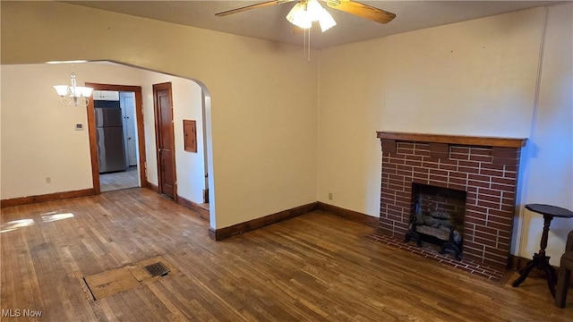 1014 20th St, Parkersburg, WV 26101 - unfurnished living room featuring wood finished floors, a ceiling fan, a tiled fireplace, arched walkways, and a chandelier
