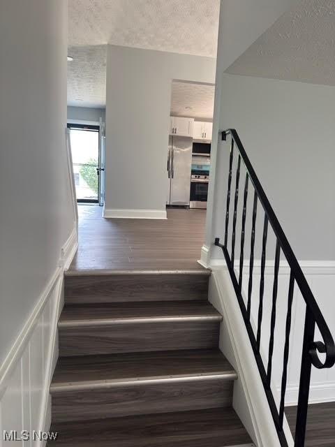 275 Butternut Ln, Berea, OH 44017 - staircase with a textured ceiling, wood finished floors, and a wainscoted wall