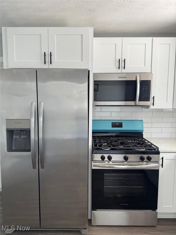 275 Butternut Ln, Berea, OH 44017 - kitchen featuring stainless steel appliances, white cabinets, backsplash, light countertops, and a textured ceiling