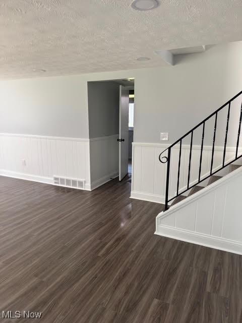 275 Butternut Ln, Berea, OH 44017 - empty room with a textured ceiling, dark wood finished floors, wainscoting, and stairs
