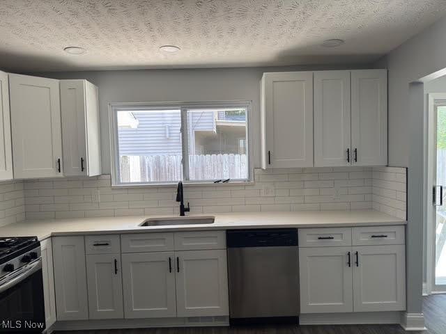 275 Butternut Ln, Berea, OH 44017 - kitchen with appliances with stainless steel finishes, white cabinetry, light countertops, tasteful backsplash, and a textured ceiling